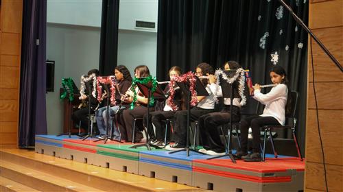 Kelly School students seated on a stage using flutes at a Winter Concert